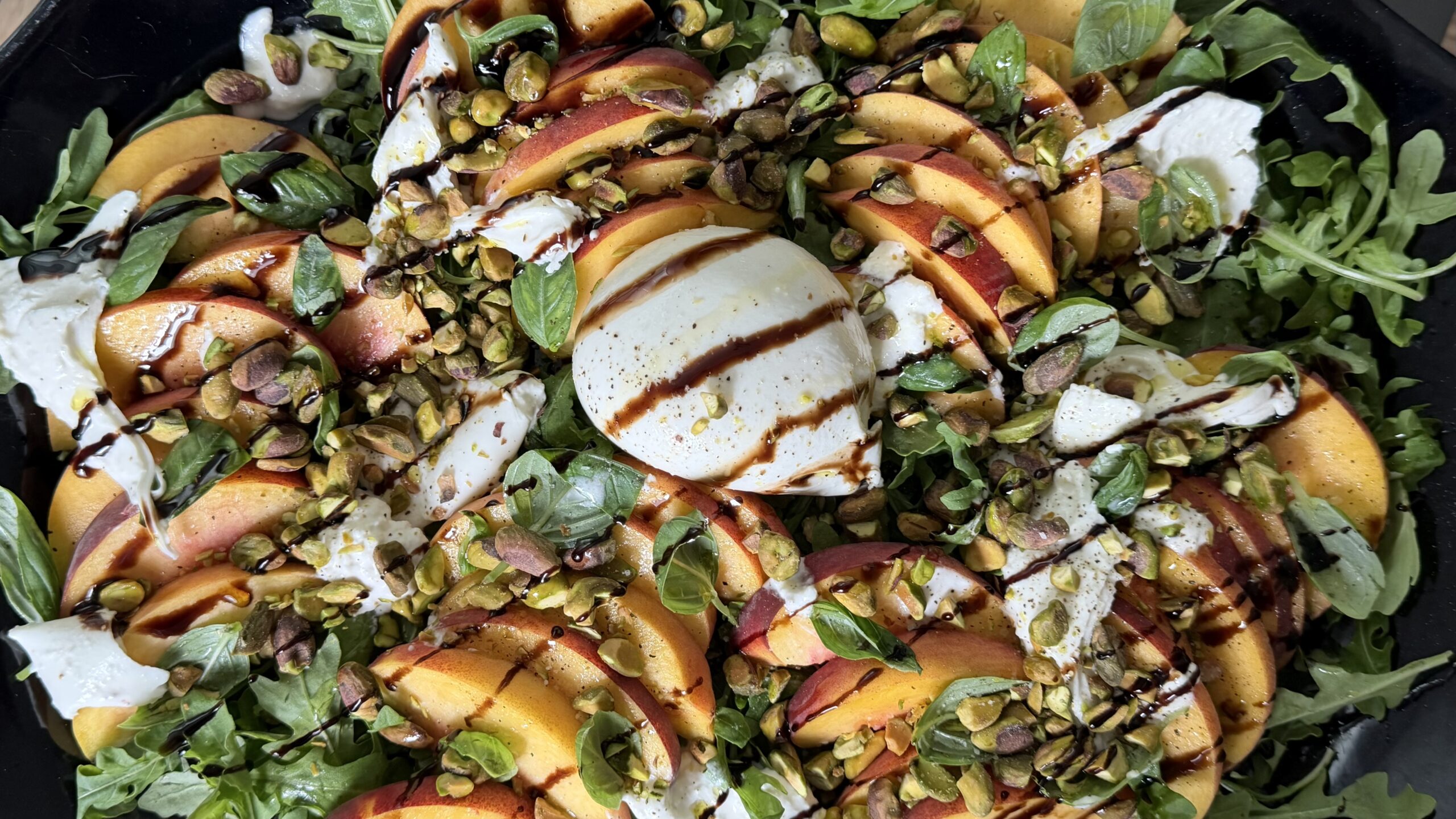 Peach and burrata salad with tomatoes, basil, pistachios and balsamic glaze