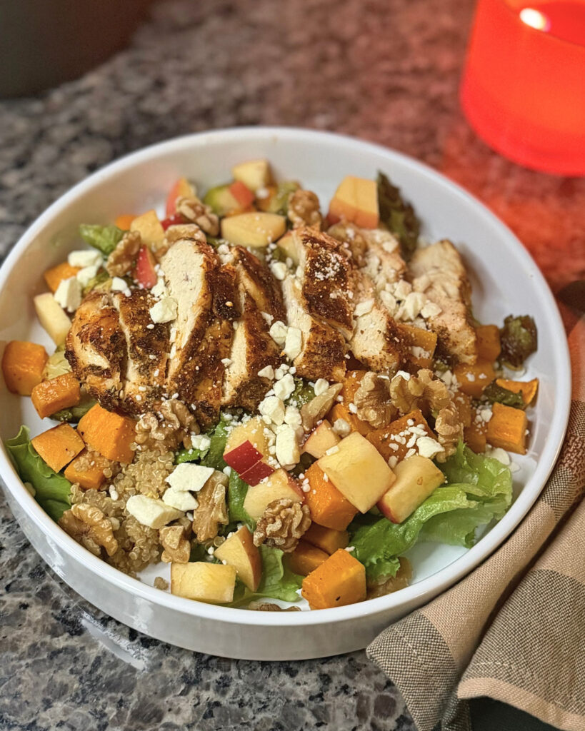 Chicken harvest bowl with quinoa, sweet potatoes, Brussels sprouts, apple, walnuts, and crumbled cheese